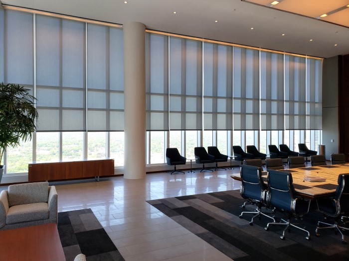 Commercial interior with large roller shades installed across a wall of windows