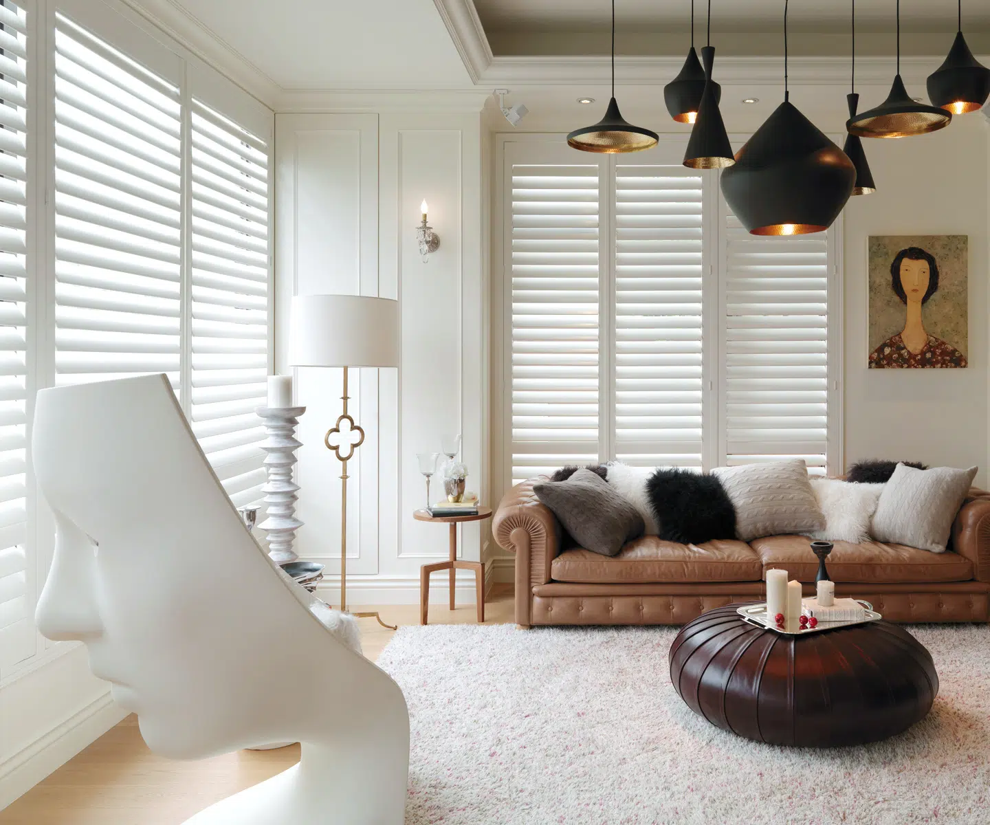 Bright living room with white plantation shutters installed across wide windows